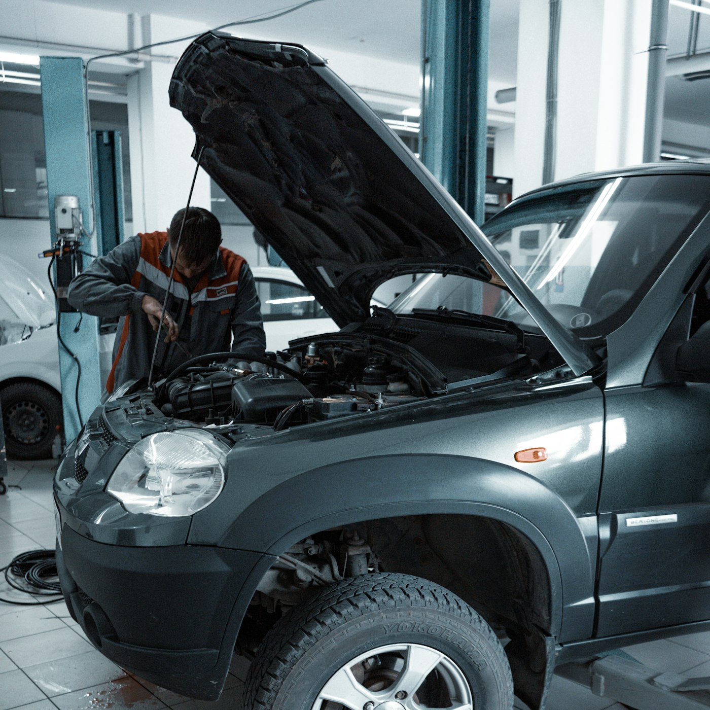 Technician inspecting an open engine bay in a workshop